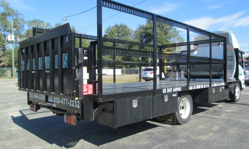 Flatbed with Tommy Gate G2 lift gate and E-track side rails for transporting portable toilets.
